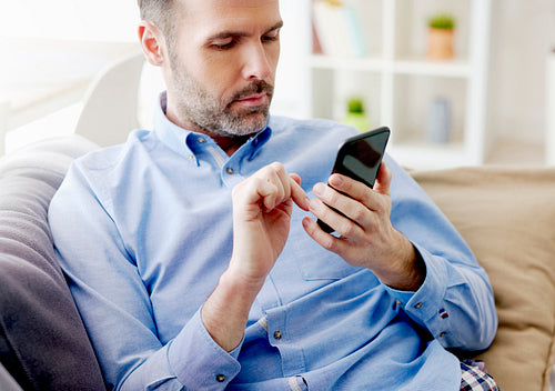 Man sitting on sofa and browsing a phone