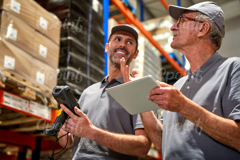Two caucasian men in mature age discussing together in warehouse 