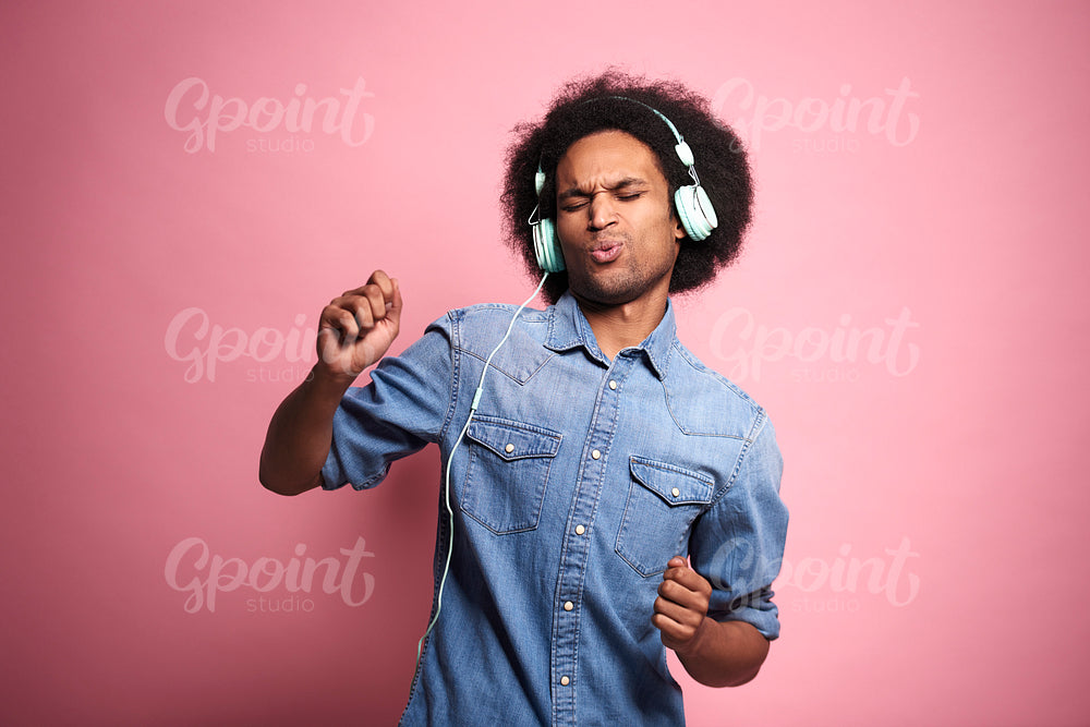African man listening to music and dancing in studio shot.