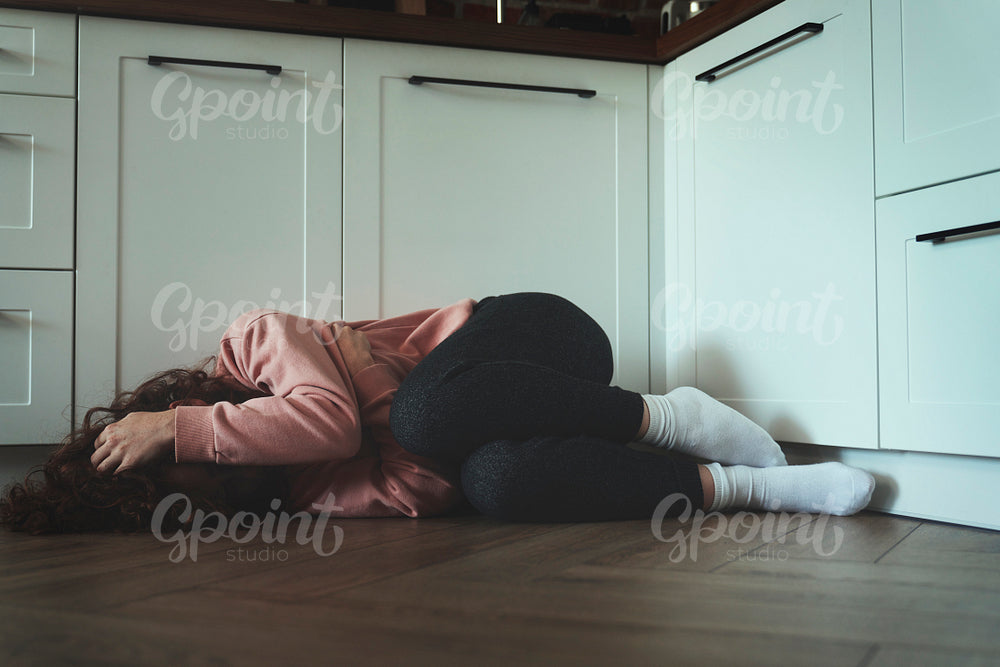 Young woman with covered face lying on floor in the kitchen
