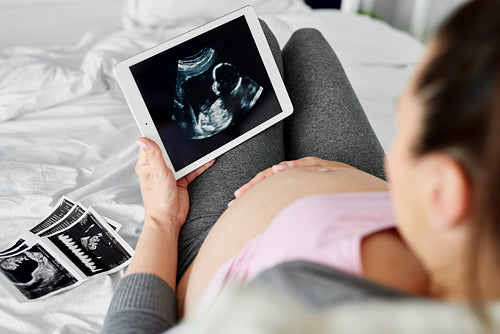 Rear view of pregnant woman browsing ultrasound image on tablet