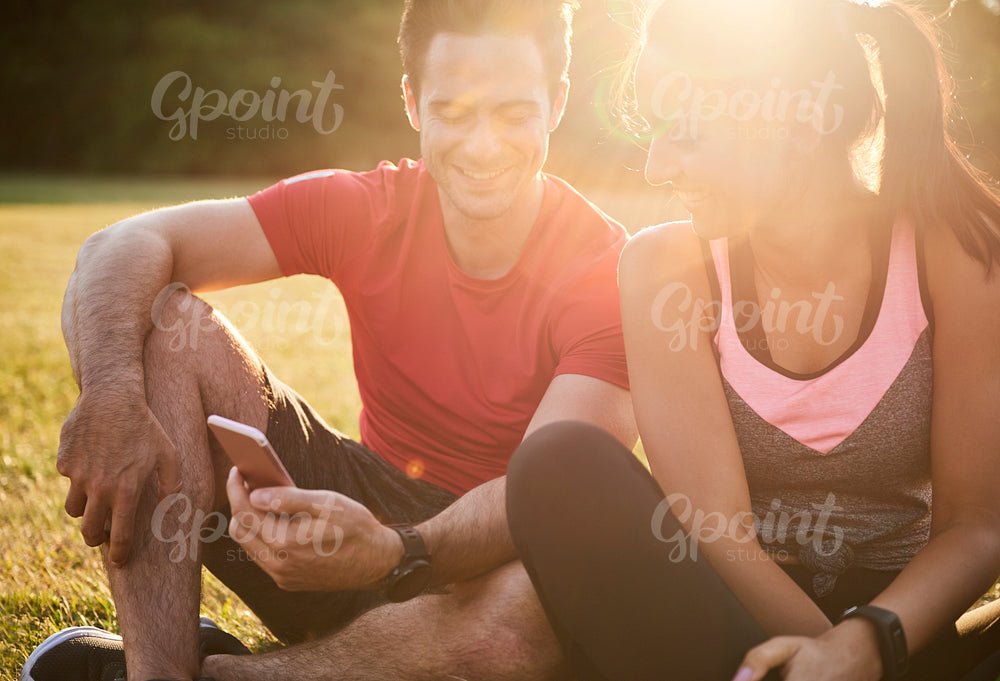 Happy couple using mobile phone after hard workout