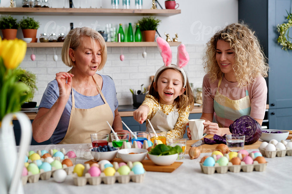 Front view of three generations of woman during coloring eggs