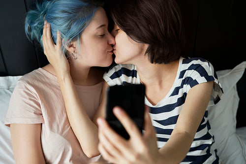 Lesbian couple taking a selfie while kissing