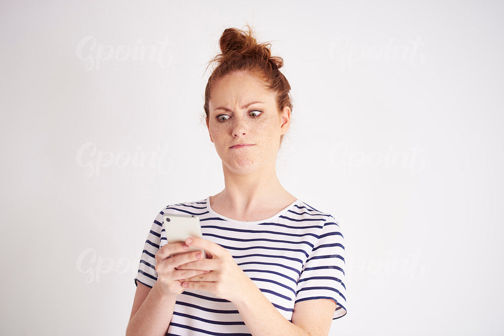 Furious woman using mobile phone at studio shot