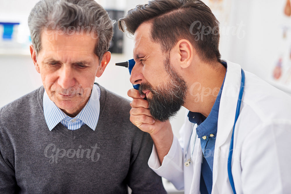 Doctor examining ear of senior man