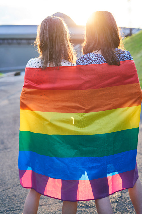 Rear view of two women standing with the rainbow flag