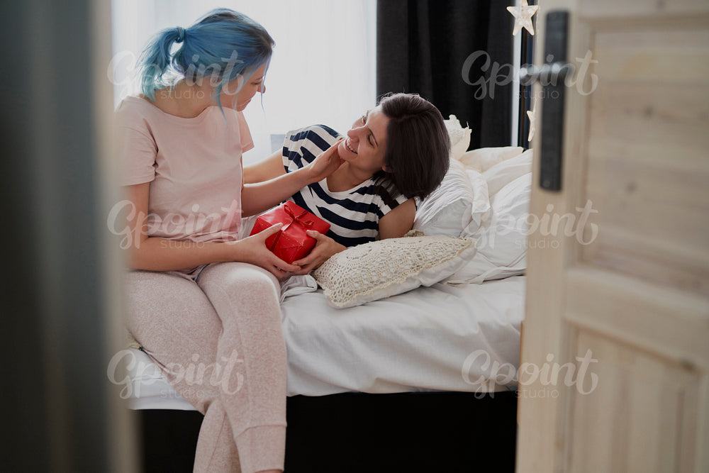 Happy lesbian couple giving Christmas gift on the morning