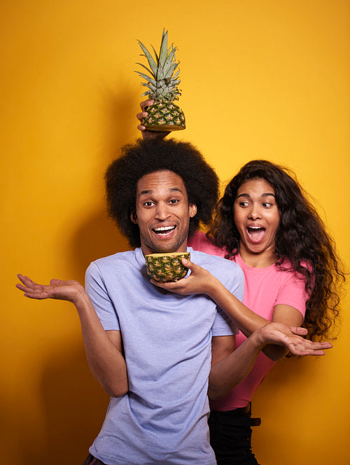 Cheerful Afroamerican couple and tasty pineapple