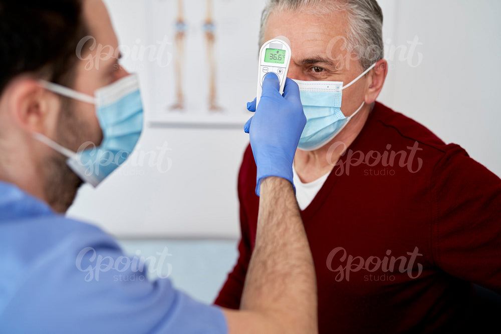 Doctor measuring the temperature of the senior man