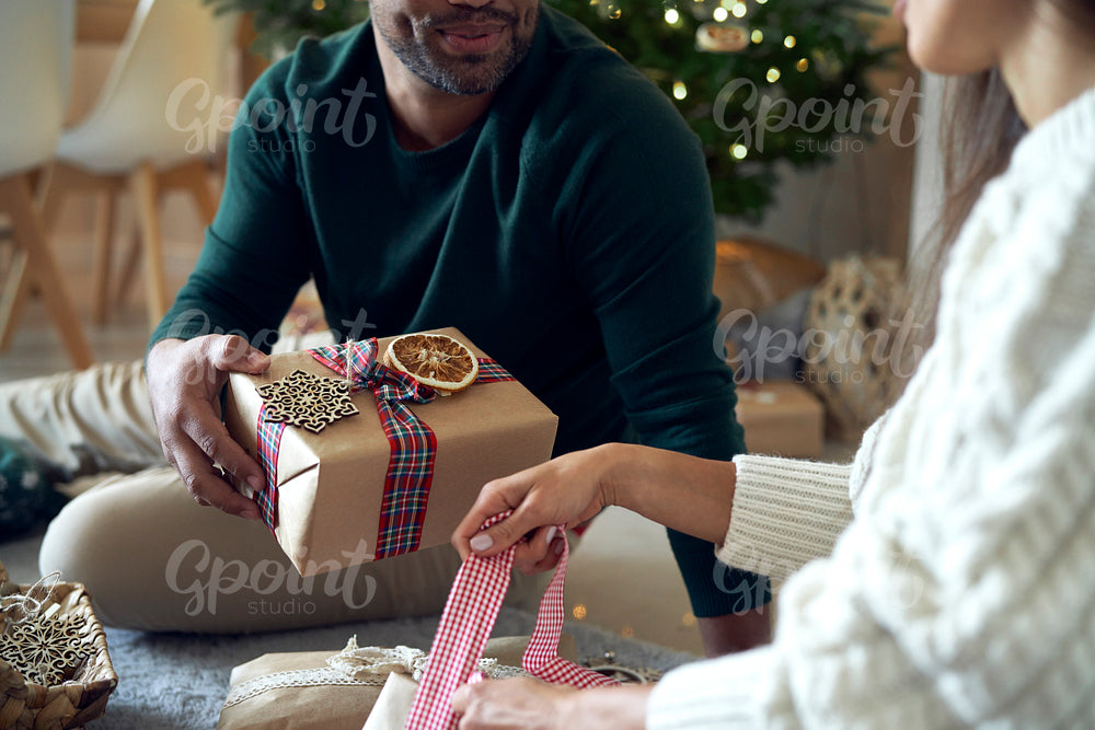 Happy couple packing Christmas present together at home 