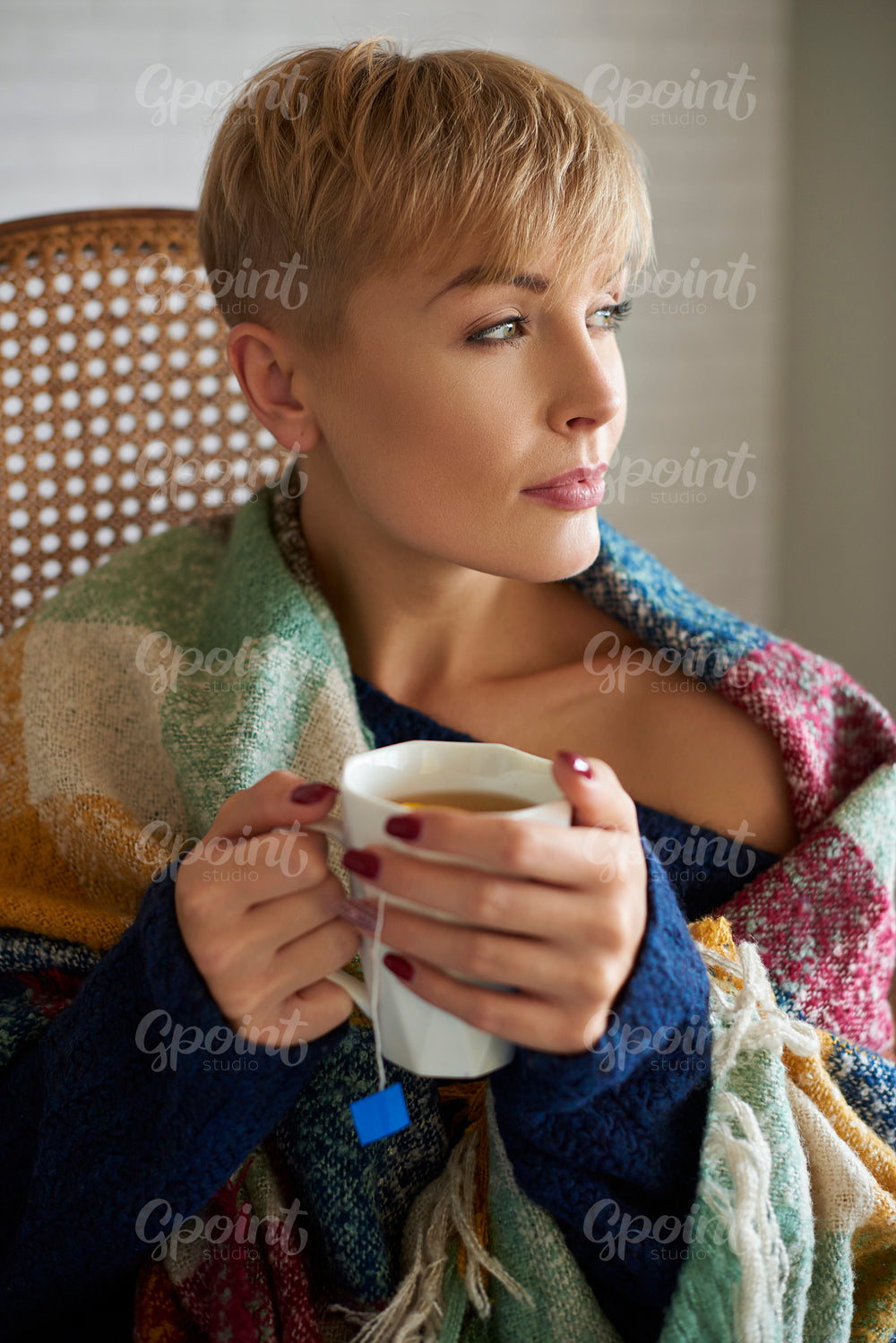 Woman wrapped in a blanket drinking hot tea