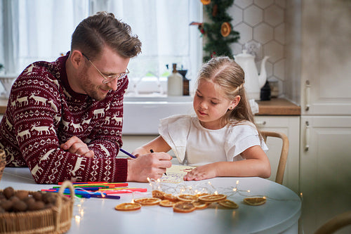 Little girl writing letter to Santa Claus with daddy