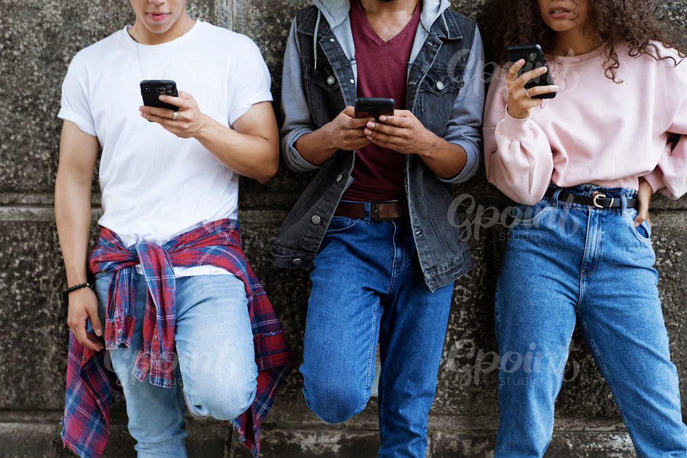 Front view of unrecognizable young people standing with mobile phones