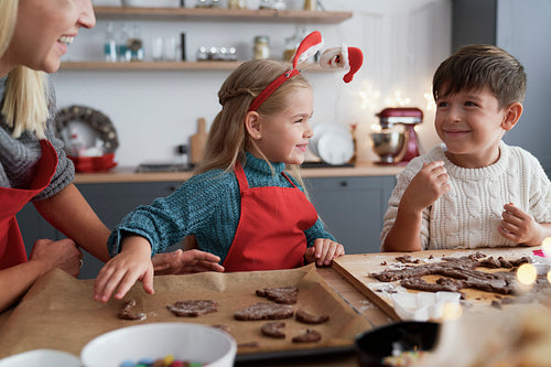 Two children and their mother cutting out gingerbread cookies