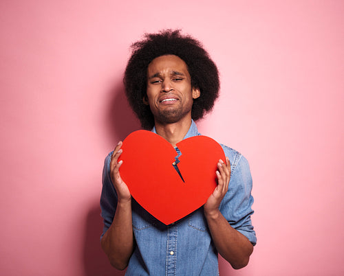 Portrait of distraught African man with a broken red heart.