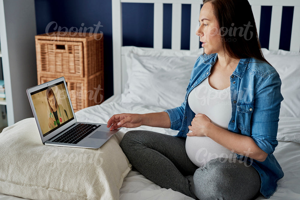 Pregnant woman having a video call with a doctor