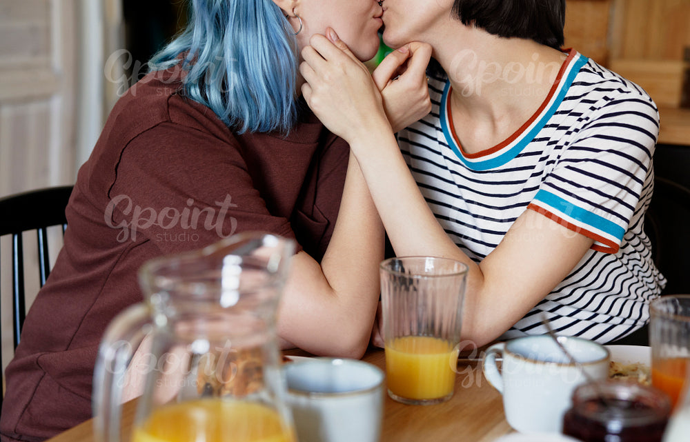 Unrecognizable lesbian couple kissing during breakfast