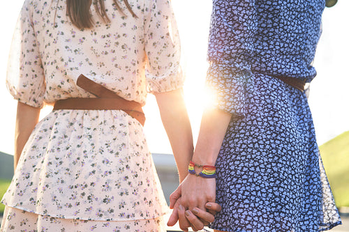 Rear view of two women holding hands during sunset