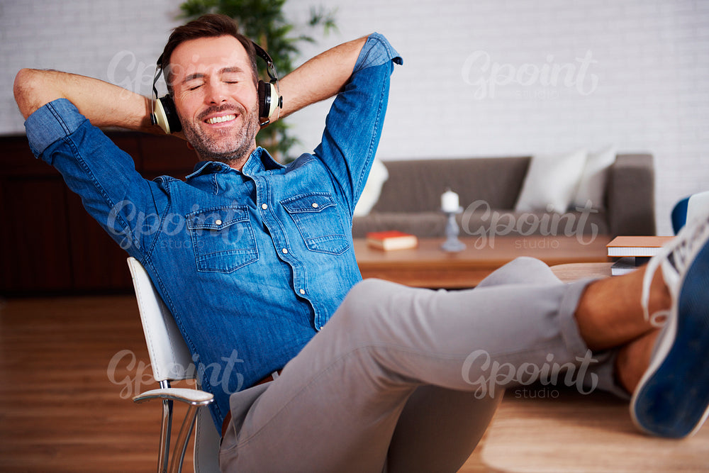 Satisfied man resting and listening to music in his office