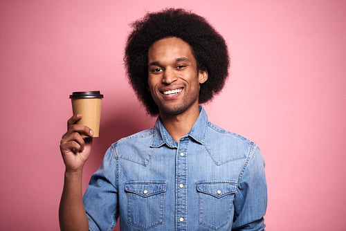 Smiling African man by coffee mug in studio shot.