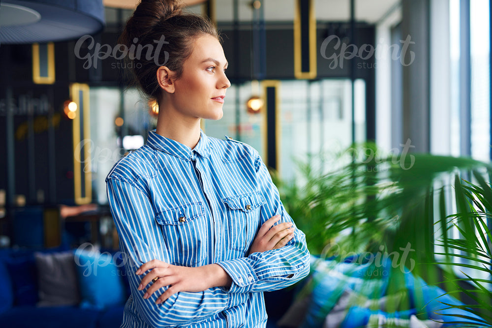 Serious woman looking through window in the office