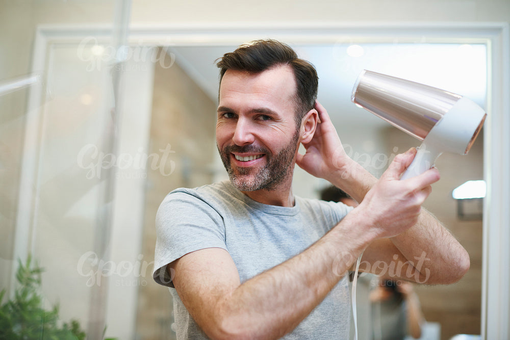Portrait of man drying his hair in bathroom