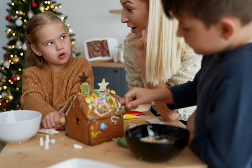 Family talking while decorating gingerbread house
