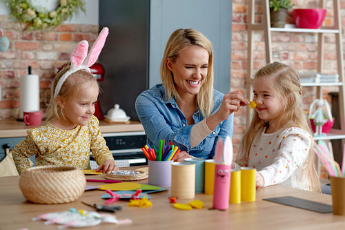 Mother and two little daughters have fun making Easter decorations