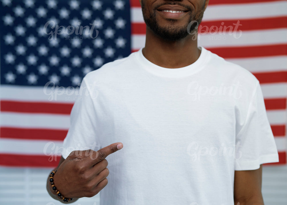 Cheerful black man pointing on white t-shirt