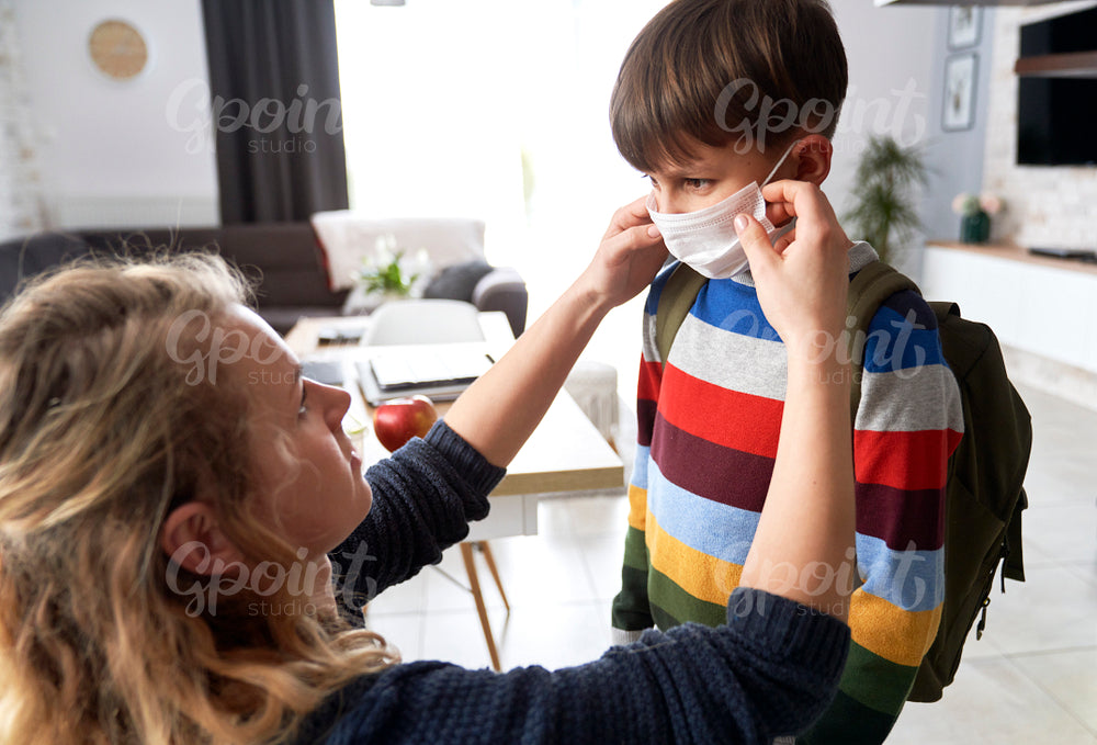 Mother puts on a protective mask for her son
