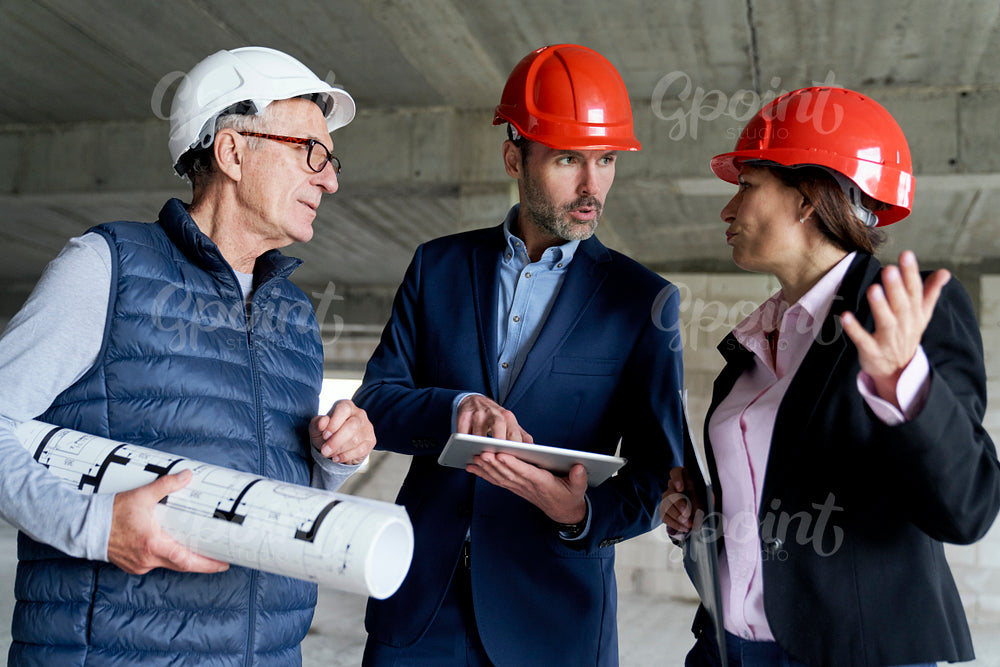 Medium shot of group of  caucasian engineers and investors discussing on construction site 