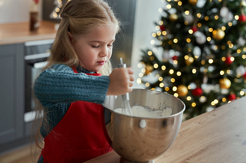 Little girl baking a cake herself