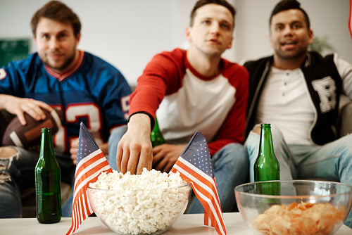 Unrecognizable football fans snacking at home