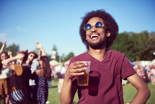 Happy African man drinking beer in festival