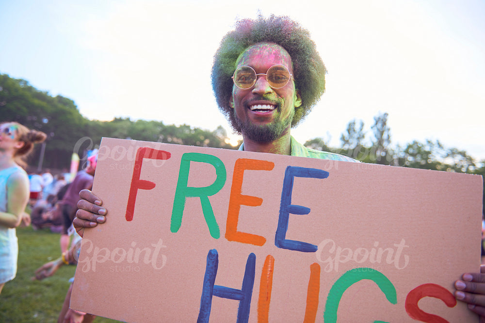 African man holding banner "free hugs" at music festival