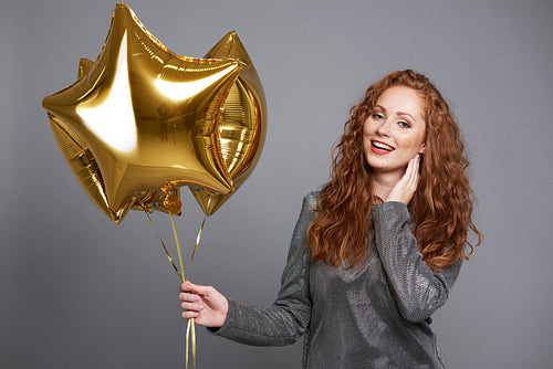 Smiling woman holding star shaped balloons