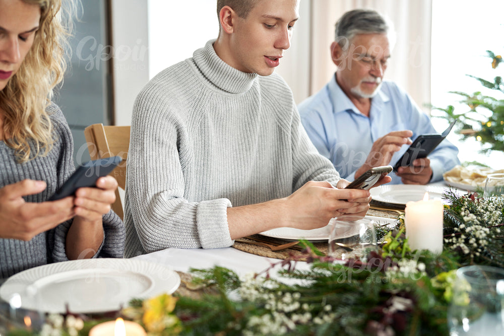 Family of caucasian people sitting in silence and using phones during Christmas Eve 