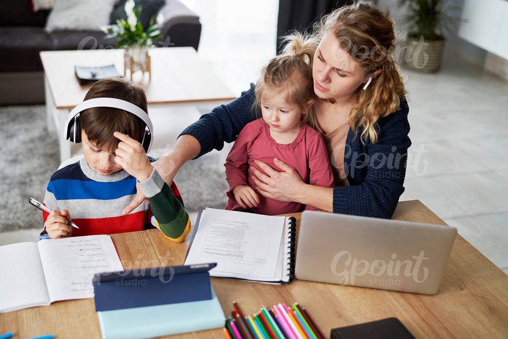 Mother during home office and helping children in education