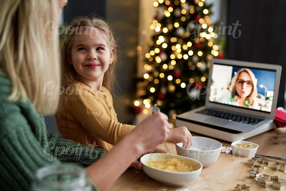 Mother and daughter in kitchen during video conference with grandma