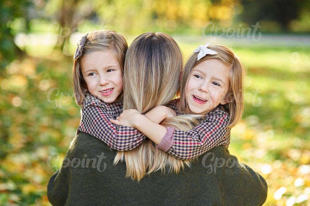 Two little girls embracing their mom