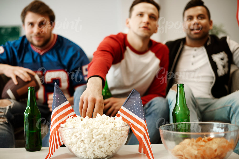 Unrecognizable football fans snacking at home