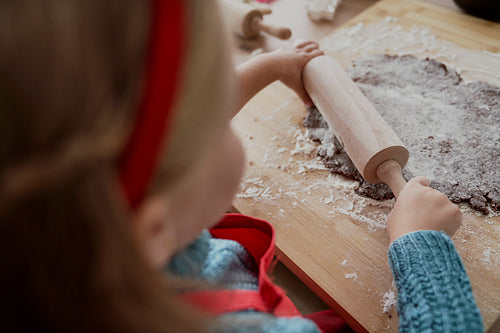 Rear view of little girl rolling gingerbread dough