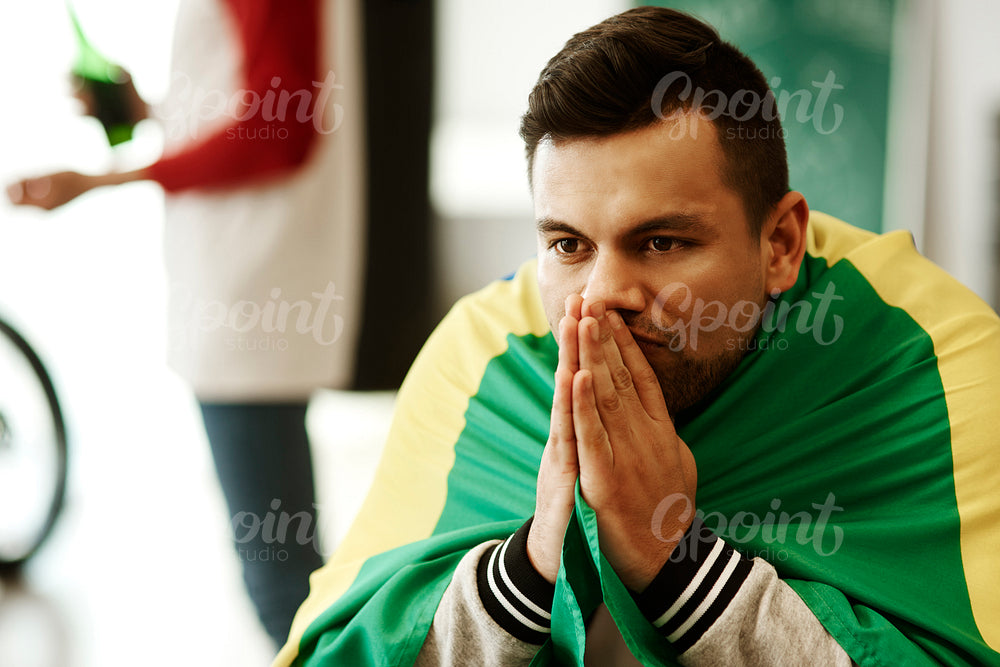 Nervous football fan with flag praying
