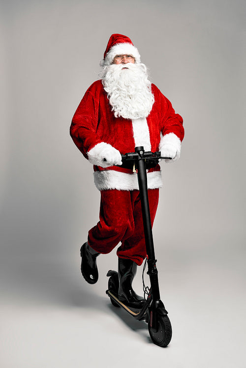 Caucasian Santa Claus riding an electric scooter