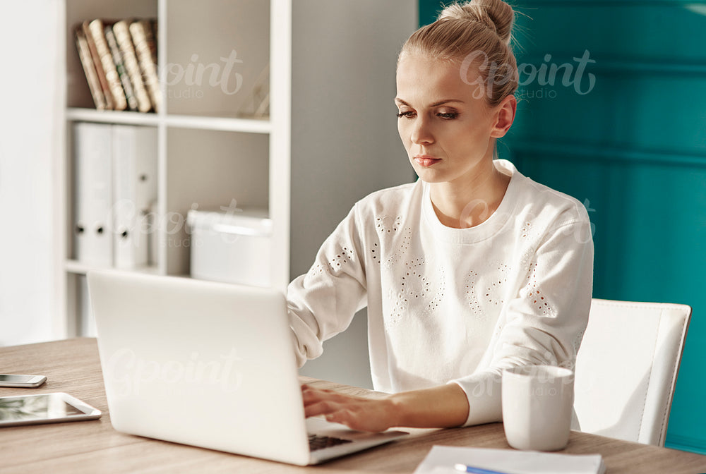 Serious woman with laptop working at home office