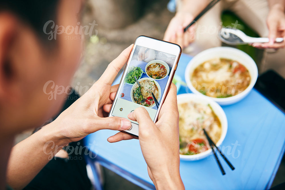 Close up of man photographing his Vietnamese food