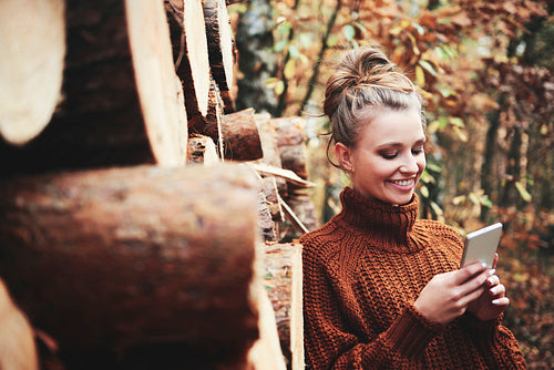 Smiling beautiful woman using digital phone in the autumn forest