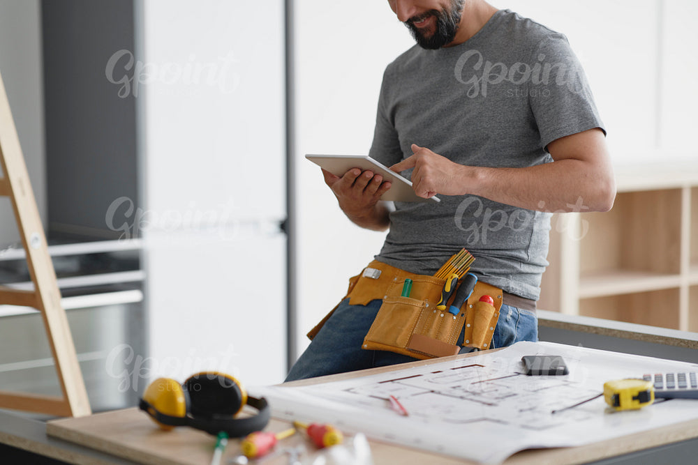 Smiling carpenter looking at something on a tablet