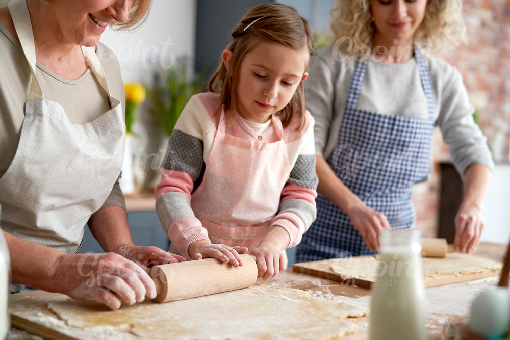Three generations of women rolling the dough for Easter cookies